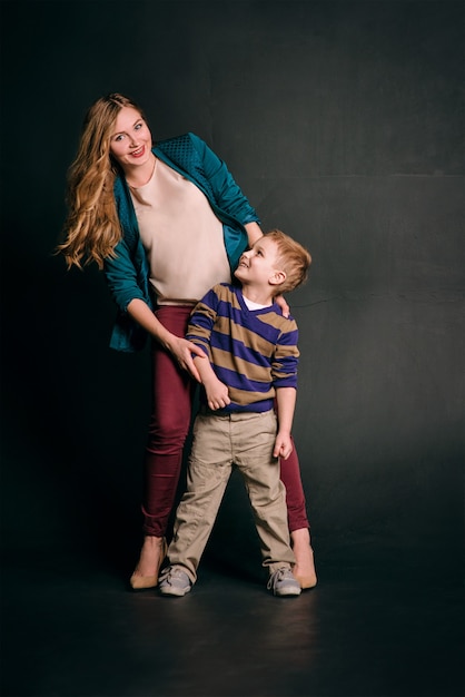 portrait of stylish cute little boy with beautiful mom in photo studio