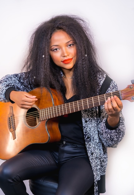 Portrait of stylish female musician holding an acoustic guitar on her shoulder