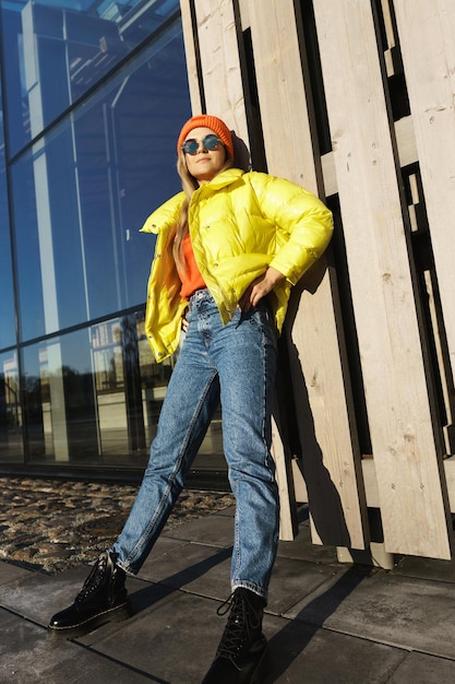 Portrait of  stylish girl wearing yellow puffer and orange knitted hat