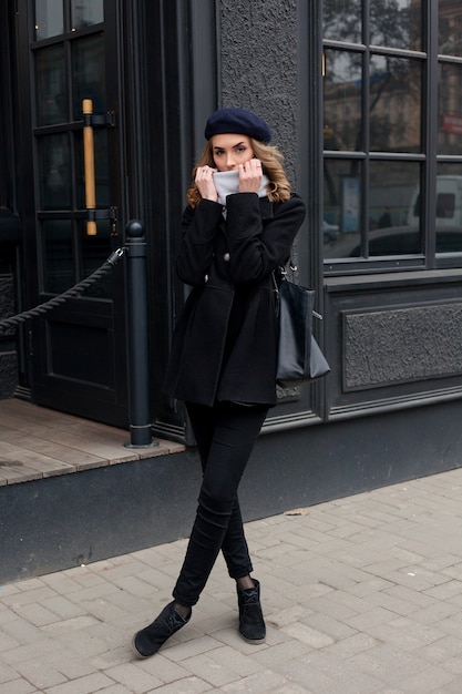 Portrait of stylish girl with wavy hair posing on the street