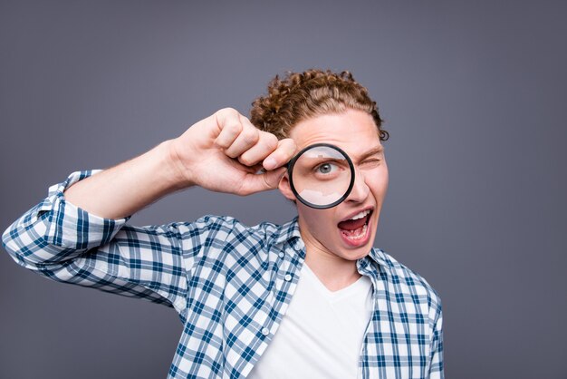 Portrait of stylish guy wavy hair in casual checkered shirt one eye looking loupe