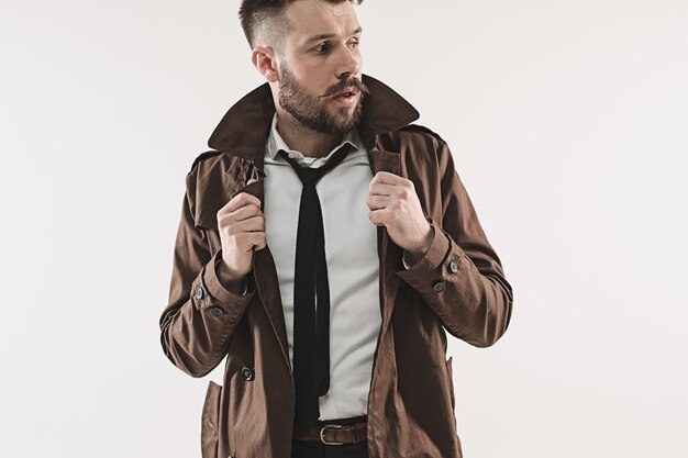 Portrait of stylish handsome young man standing at studio against white. Man wearing jacket