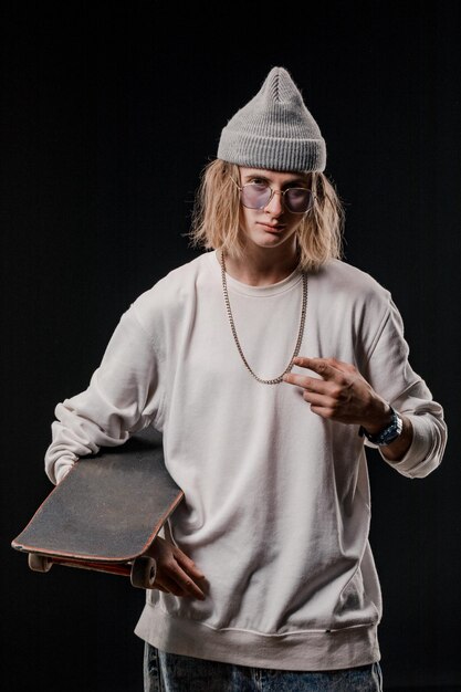 Portrait of a stylish man holding a skateboard in the Studio Closeup of a smiling skateboarder posing on a black background