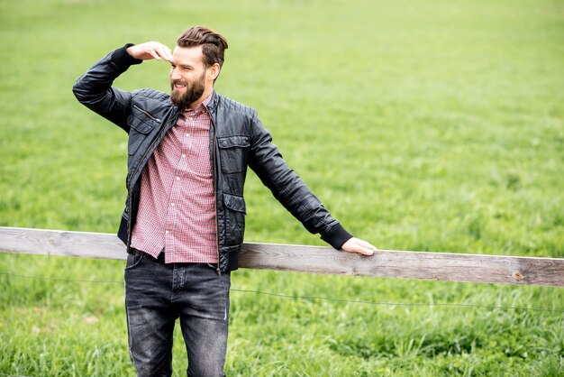 Portrait of a stylish man outdoors at the countryside on the green meadow background