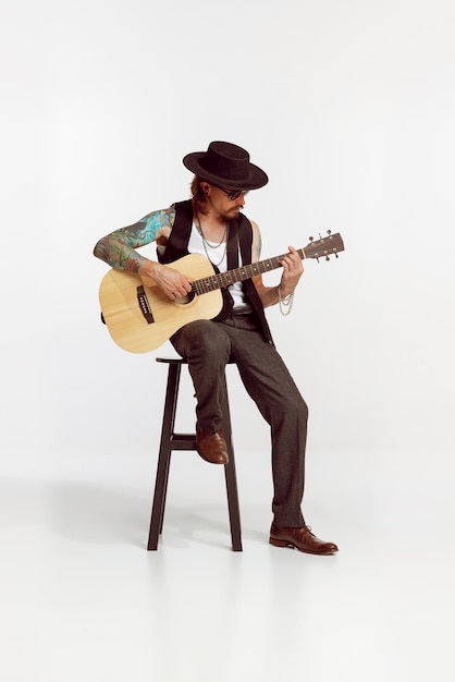 Portrait of stylish man rock musician playing guitar performing\
isolated over white studio