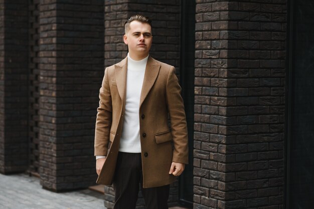 Portrait of a stylish man with a beard dressed in a coat, outdoors