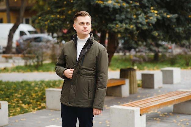 Ritratto di un uomo alla moda con la barba vestito con un cappotto, all'aperto