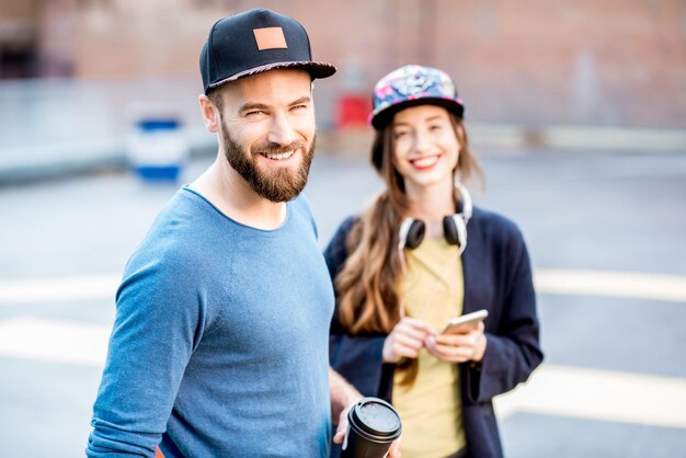 Portrait of a stylish man and woman in caps standing together outdoors on the playground