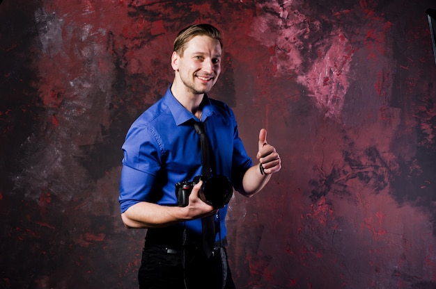 Портрет стильный профессиональный фотограф человек с камерой, носить синюю рубашку и галстук.