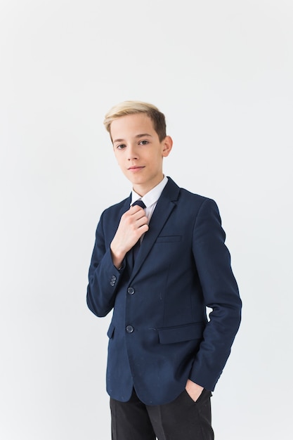 Portrait of stylish school boy teenager in white shirt and jacket against white surface.