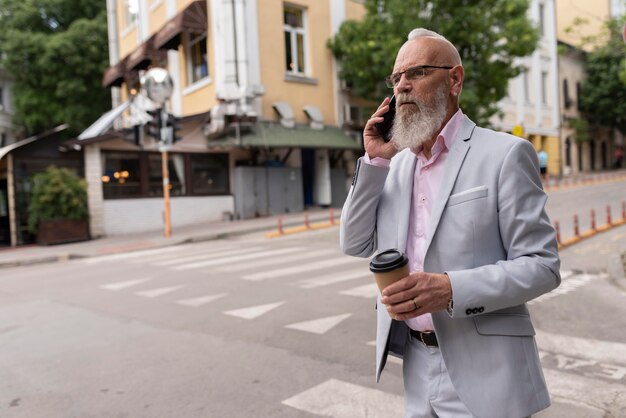 Ritratto di un uomo anziano alla moda che parla al telefono