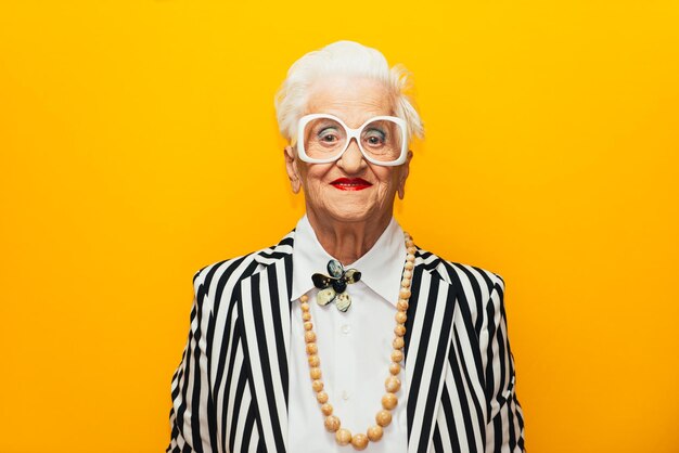 Photo portrait of stylish senior woman standing against yellow background