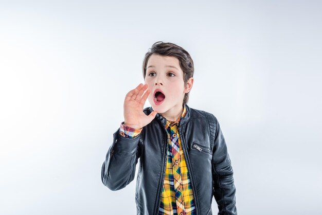 Portrait of stylish shouting boy isolated on grey