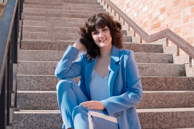 Portrait of a stylish smiling business woman in fashionable clothes in a big city, purposefully looking at the camera.