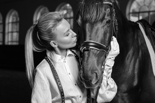 Foto ritratto di una donna alla moda che abbraccia un cavallo purosangue. concetto di amore e cura. tecnica mista