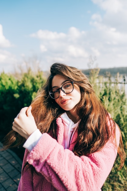 Portrait of stylish young caucasian woman with brunette hair in eyeglasses outdoor.