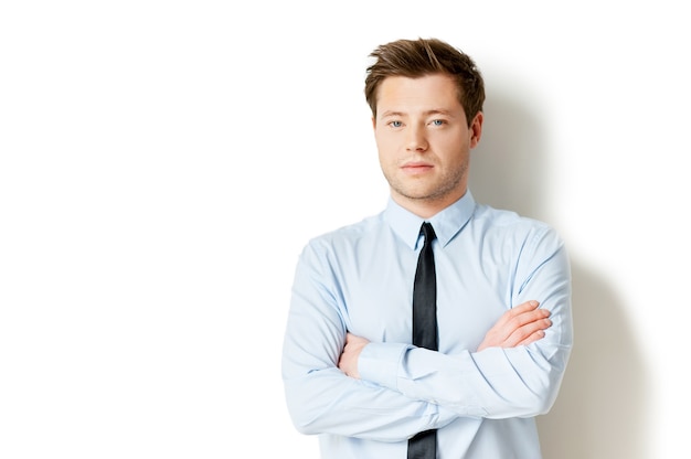 Portrait of success. Handsome young man in formalwear looking at camera and keeping arms crossed while standing isolated on white