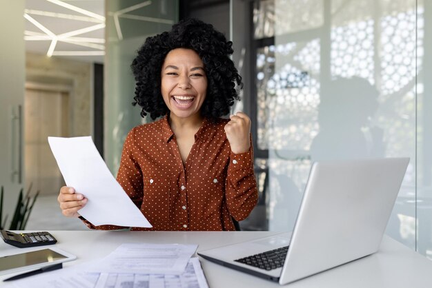 Photo portrait of successful african american woman boss at workplace businesswoman behind paper work