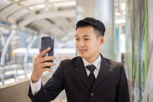 Портрет успешного азиатского бизнесмена с помощью телефона