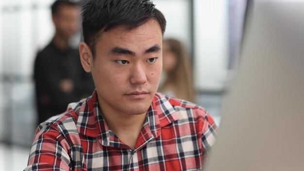 Portrait of a successful Asian software engineer working on a laptop at his desk