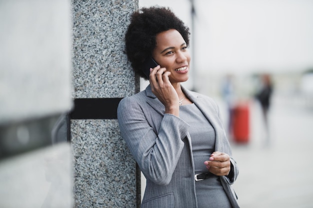 Portrait of a successful black business woman talking on a smart phone in front a corporate building.