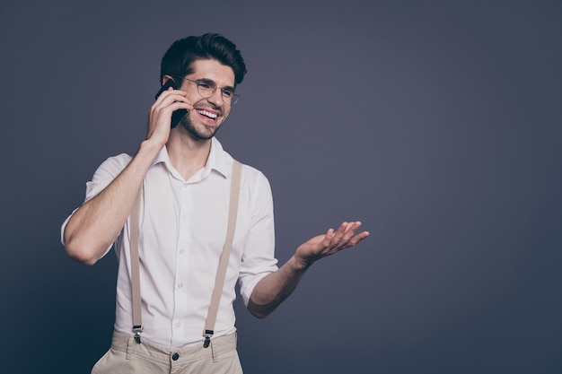 portrait of successful business man speaking telephone with partners friendly mood dressed formalwear shirt suspenders trousers specs .