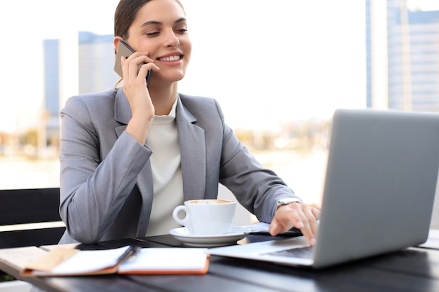 portrait of successful business woman talking on the phone and smiling while working in the modern cafe.