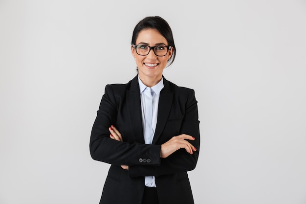 Portrait of successful businesswoman 30s in formal wear and eyeglasses standing in the office, isolated over white wall