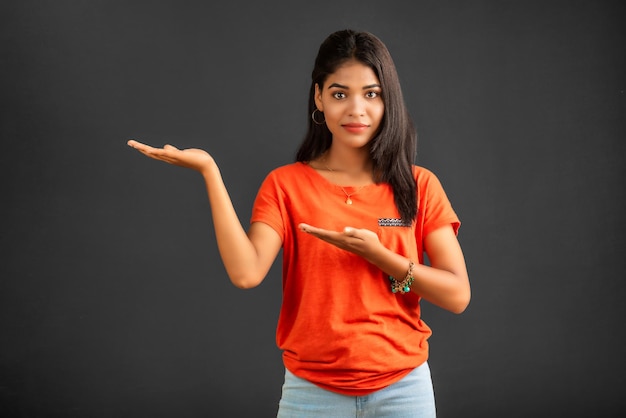 Portrait of a successful cheerful young girl holding and presenting something on hand with a happy smiling face