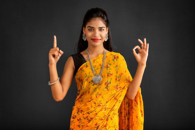 Photo portrait of a successful cheerful young girl pointing and presenting something with hand or finger with a happy smiling face