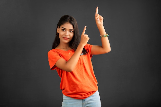 Ritratto di una ragazza allegra di successo che punta e presenta qualcosa con la mano o il dito con una faccia sorridente felice