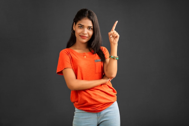 Portrait of a successful cheerful young girl pointing and presenting something with hand or finger with a happy smiling face