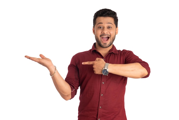 Portrait of a successful cheerful young man holding and presenting something on hand with a happy smiling face