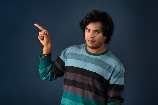 Portrait of a successful cheerful young man pointing and presenting something with hand or finger with a happy smiling face