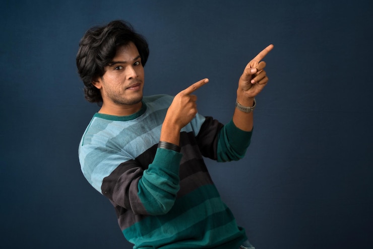फोटो portrait of a successful cheerful young man pointing and presenting something with hand or finger with a happy smiling face