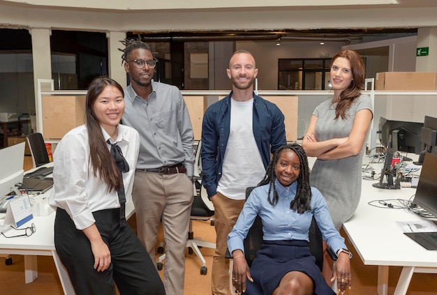 Foto ritratto di un team di business multietnico creativo di successo che guarda la telecamera e sorride in uno spazio di coworking