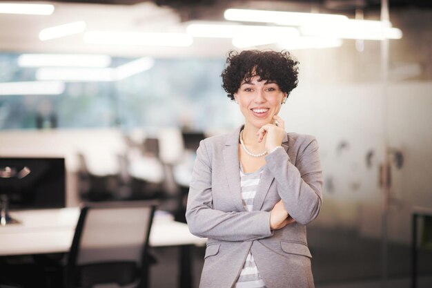 Portrait of successful female software developer with a curly hairstyle at modern startup office