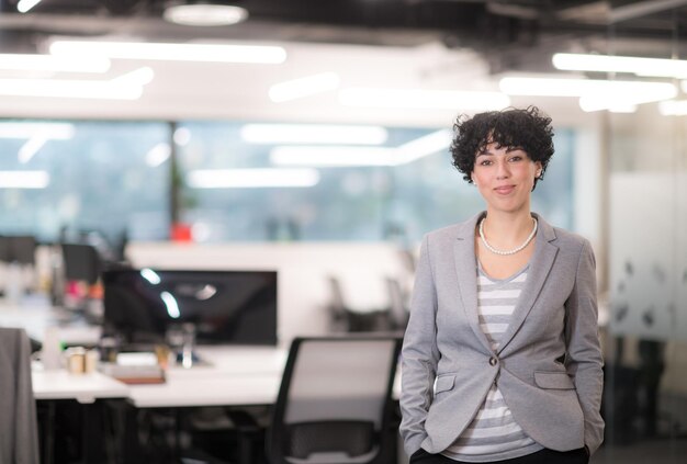 Портрет успешной женщины-разработчика программного обеспечения с кудрявой прической в современном стартап-офисе