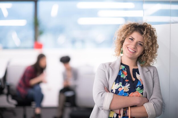 Portrait of successful female software developer with a curly hairstyle at modern startup office