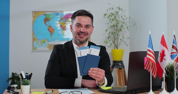 Photo portrait of successful happy man travel agent in a travel agency with passports and tickets the concept of tourism and travel