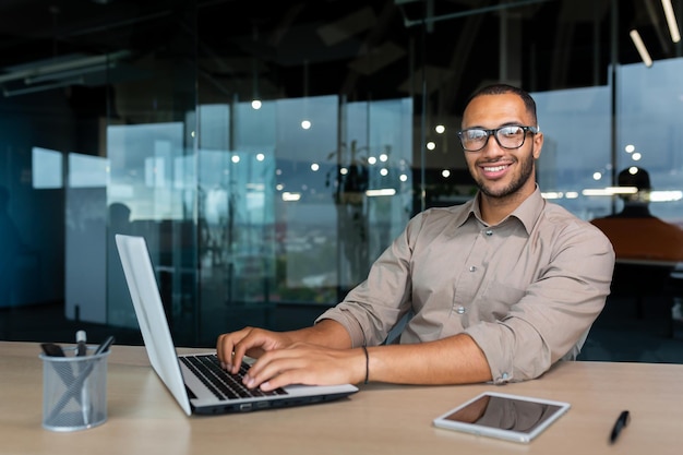 Portrait of successful hispanic businessman inside office man with laptop working typing on keyboard