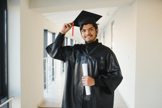 Ritratto di studente indiano di successo in abito di laurea.