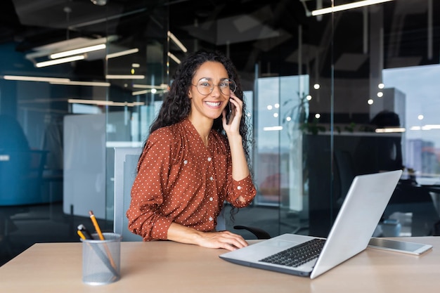 Portrait of successful latin american business woman office worker smiling and talking on phone