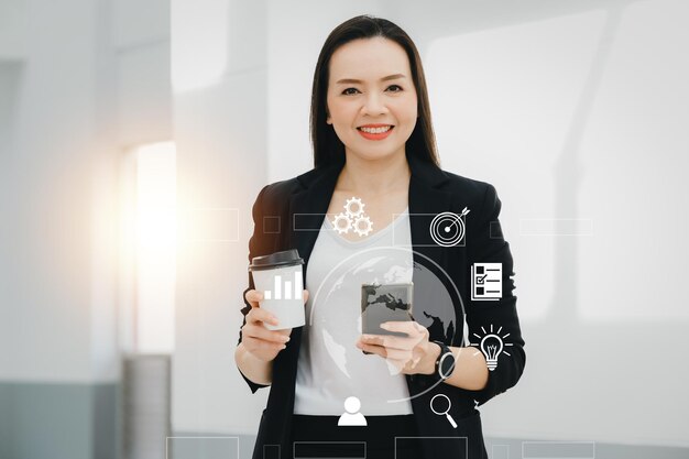 Portrait Of Successful A middle-aged Asian businesswoman Holding smart phone and coffee smiling to camera