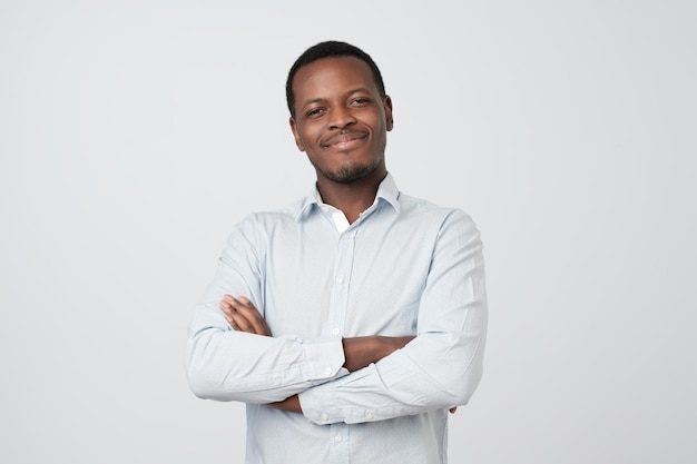 Photo portrait of successful serious handsome afroamerican man in shirt crossed hands and smiling