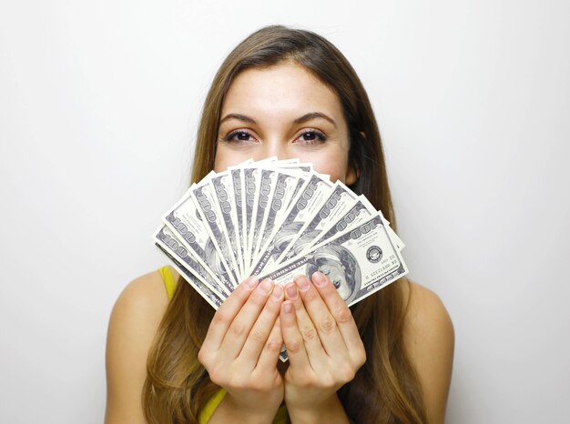 Portrait of successful woman covering mouth with fan of 100 dollar bills