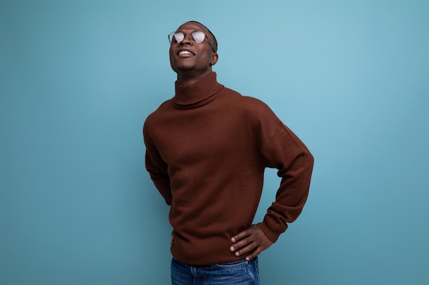 Portrait of a successful young african man of model appearance in a brown sweater isolated with copy