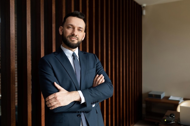 Ritratto di un giovane uomo d'affari di successo in un vestito sullo sfondo di un ufficio alla moda