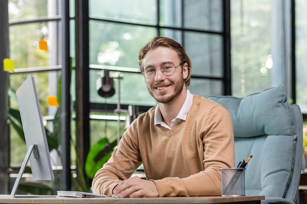 Portrait of a successful young man programmer it developer software sitting at a desk in a modern