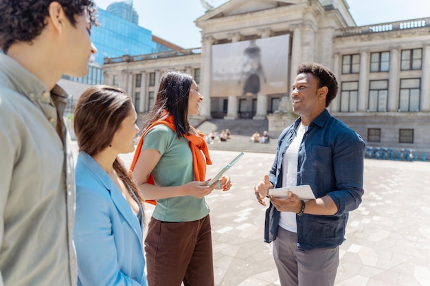 Portrait of successful young students talking near university campus outdoors